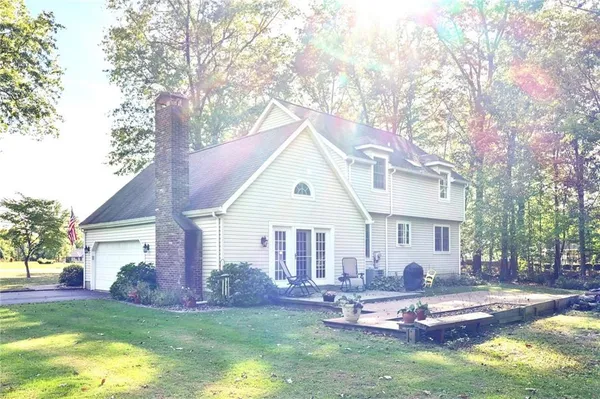a view of a house with a yard chairs and a large tree