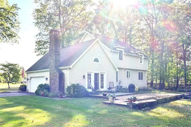 a view of a house with a yard chairs and a large tree