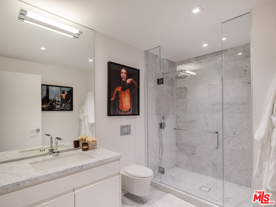 9000 West 3rd Street, Unit 103 Los Angeles, CA 90048 - Photo 14 of 27 a bathroom with a granite countertop sink a mirror a toilet and shower