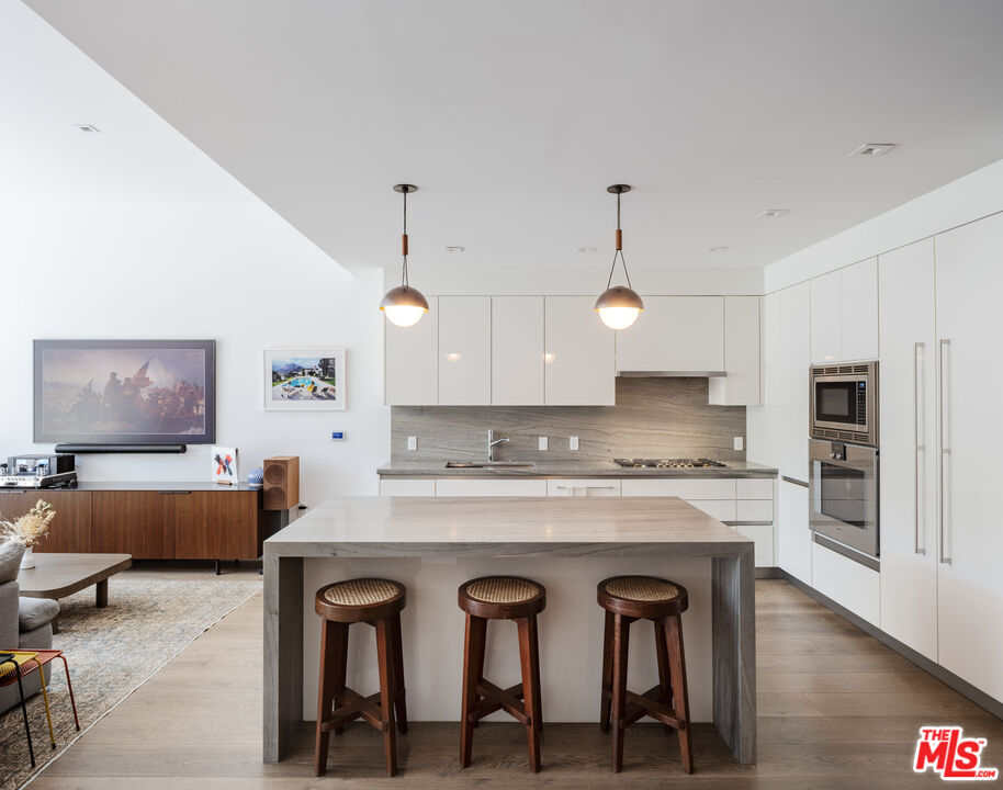 9000 West 3rd Street, Unit 103 Los Angeles, CA 90048 - Photo 4 of 27 a large kitchen with kitchen island a dining table and chairs