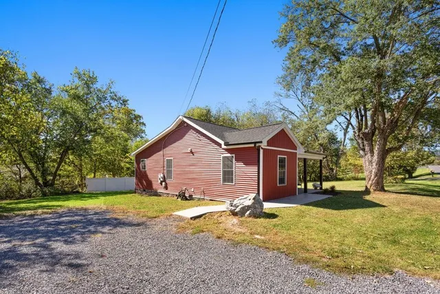 a view of a house with a yard plants and large tree