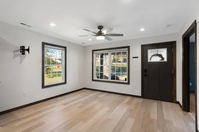 a view of an empty room with a window and wooden floor