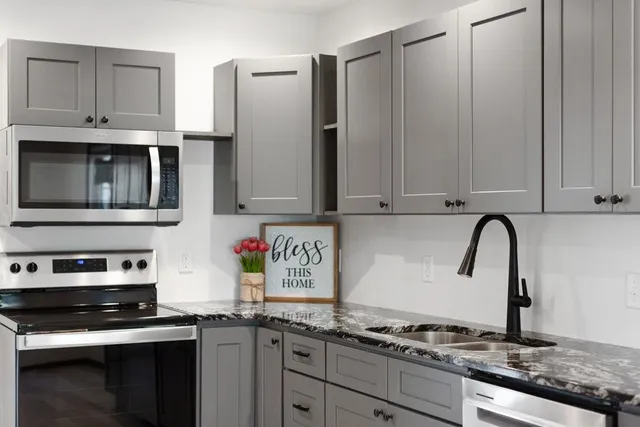 a kitchen with stainless steel appliances granite countertop a stove a sink and a white cabinets
