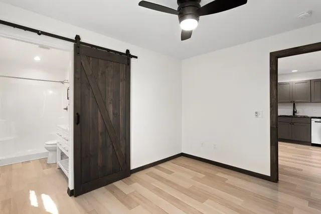 a view of a hallway with wooden floor and a bathroom