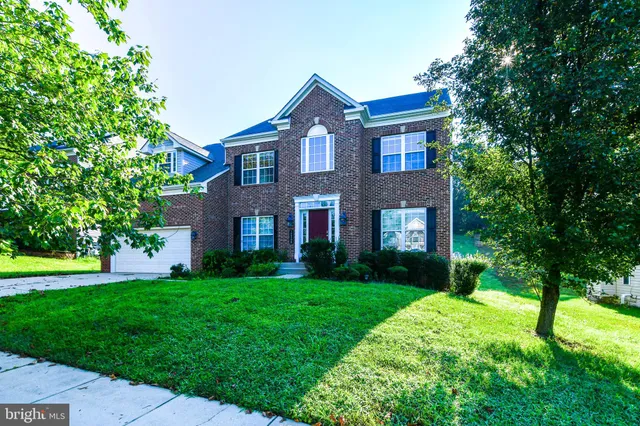 a brick house with a big yard and large trees