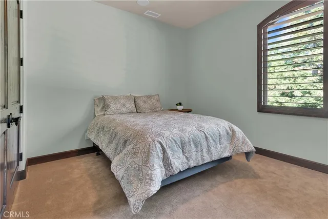 a bedroom with a bed a mirror on dresser and a chandelier