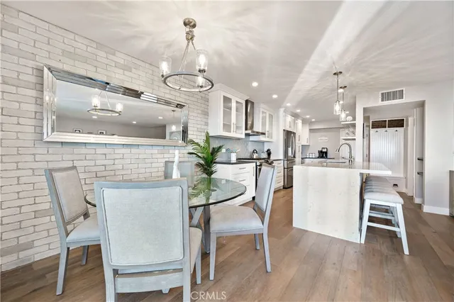 a kitchen with stainless steel appliances granite countertop a stove a sink a oven a dining table and chairs with wooden floor