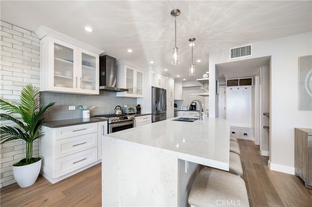 25872 Vista Drive West Dana Point, CA 92624 - Photo 15 of 75 a large kitchen with stainless steel appliances a refrigerator a sink a stove and white cabinets with wooden floor