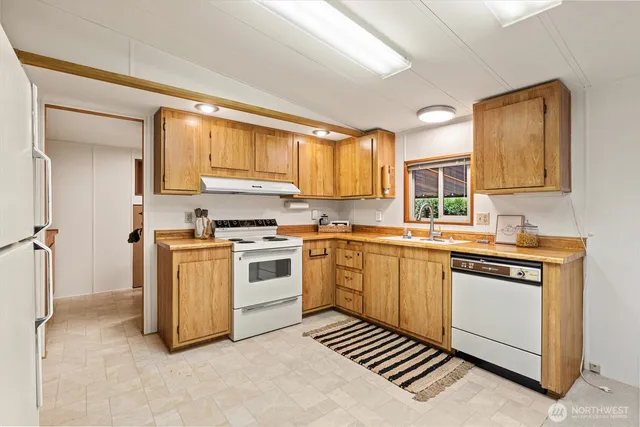 a kitchen with granite countertop a sink cabinets stainless steel appliances and a window