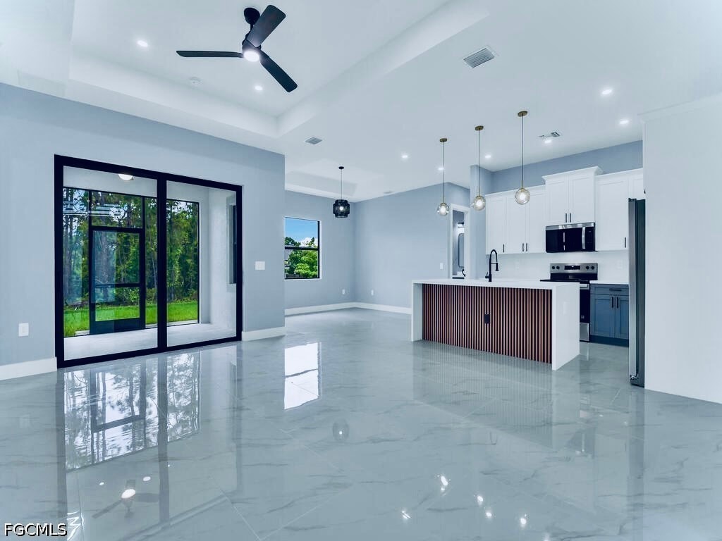 3517 2nd Street Southwest Lehigh Acres, FL 33976 - Photo 4 of 28 a large kitchen with stainless steel appliances kitchen island granite countertop a refrigerator and a stove top oven