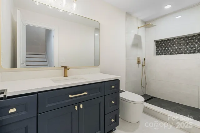 a bathroom with a sink a toilet a mirror and shower