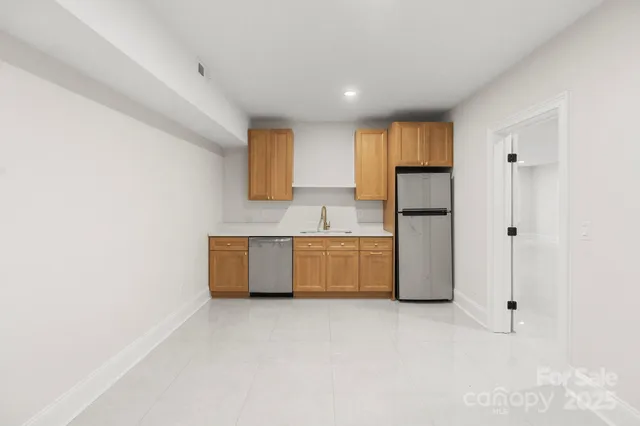 a large white kitchen with a refrigerator a stove top oven and a dishwasher