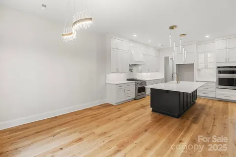 a large kitchen with stainless steel appliances kitchen island a large counter top and a wooden floors