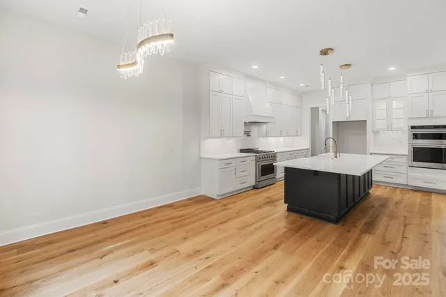 a large kitchen with stainless steel appliances kitchen island a large counter top and a wooden floors