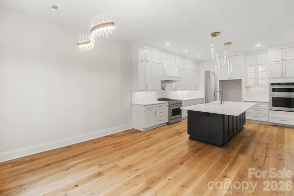 a large kitchen with stainless steel appliances kitchen island a large counter top and a wooden floors