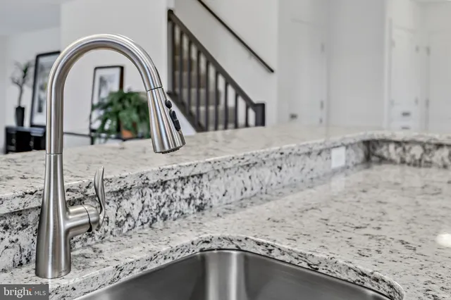 a kitchen with stainless steel appliances kitchen island granite countertop a stove a sink a refrigerator and white cabinets with wooden floor