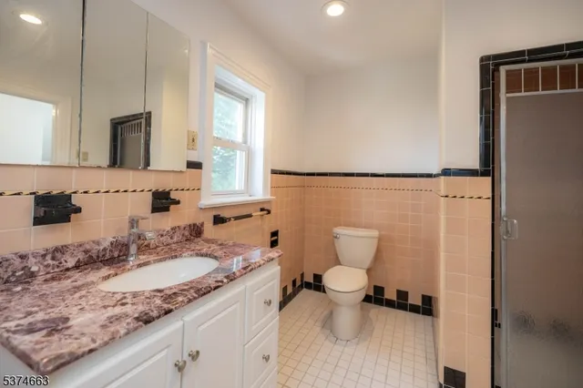a bathroom with a granite countertop sink toilet and mirror