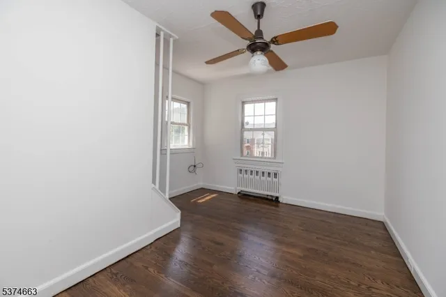 an empty room with wooden floor fan and windows