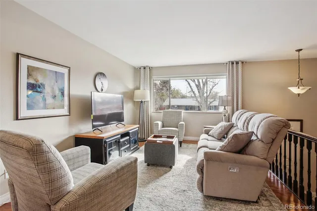 a living room with furniture two large window and a flat screen tv