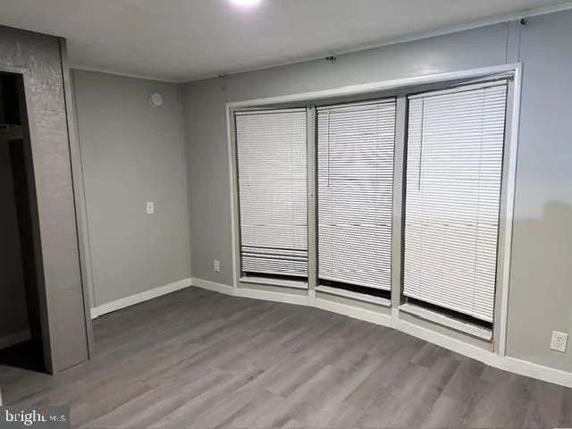 an empty room with wooden floor closet and windows