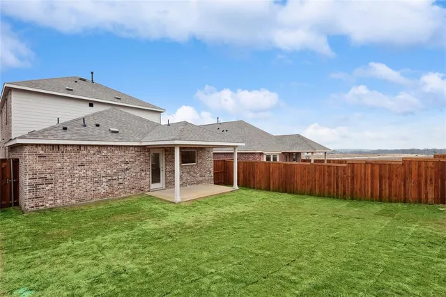 a view of a house with brick walls and a yard with wooden fence