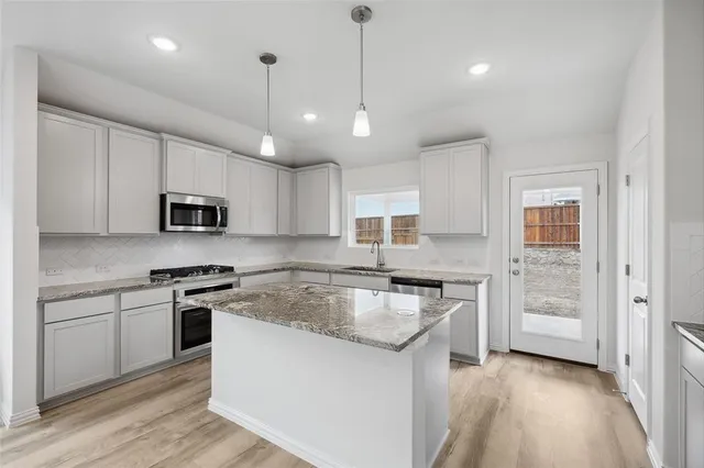 a kitchen with stainless steel appliances granite countertop a stove a sink and a refrigerator