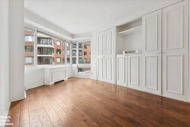 a view of an empty room with a window and wooden floor