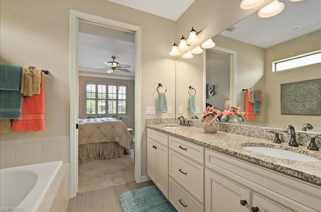 10809 Dennington Road Fort Myers, FL 33913 - Photo 17 of 30 a en suite bathroom with a granite countertop sink a mirror a bathtub and next to a window