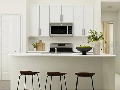 a kitchen with stainless steel appliances a microwave a stove and white cabinets