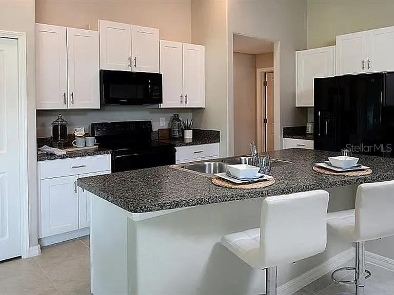 35008 Ackley Trace Zephyrhills, FL 33541 - Photo 10 of 11 a kitchen with stainless steel appliances granite countertop a sink a stove a refrigerator a dining table and chairs