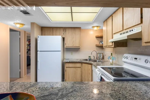 a kitchen with stainless steel appliances granite countertop a sink a refrigerator a stove a microwave and cabinets