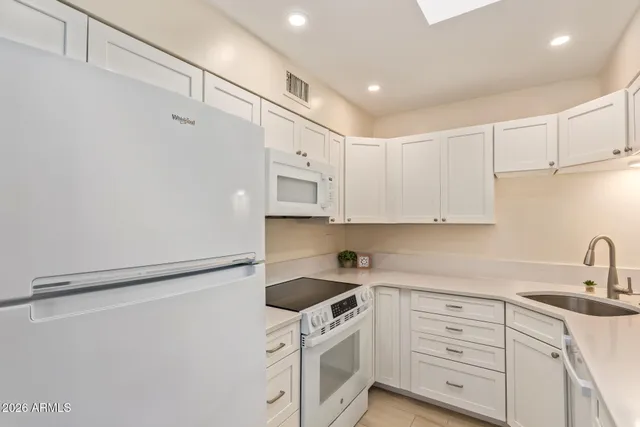 a kitchen with white cabinets and white appliances