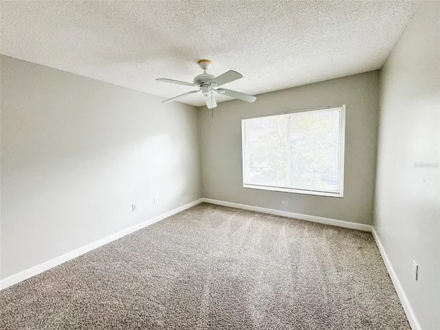 an empty room with a window and a ceiling fan
