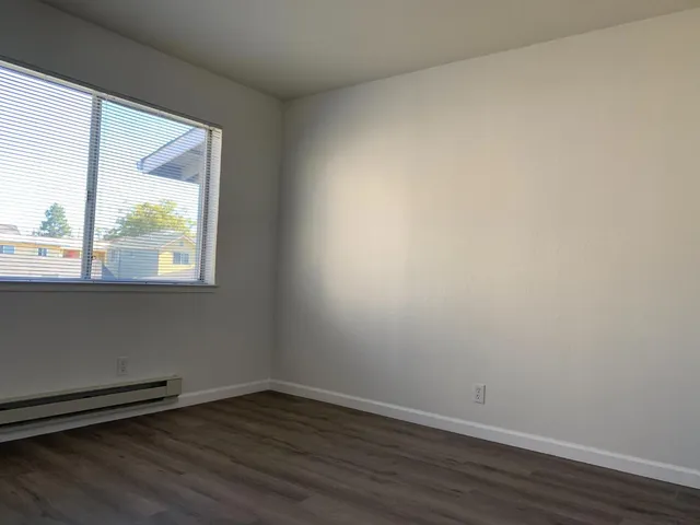 a view of an empty room and wooden floor and a window