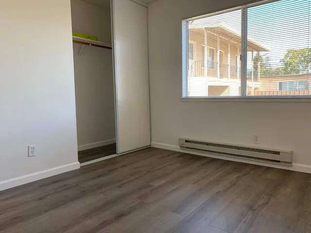 an empty room with wooden floor and windows
