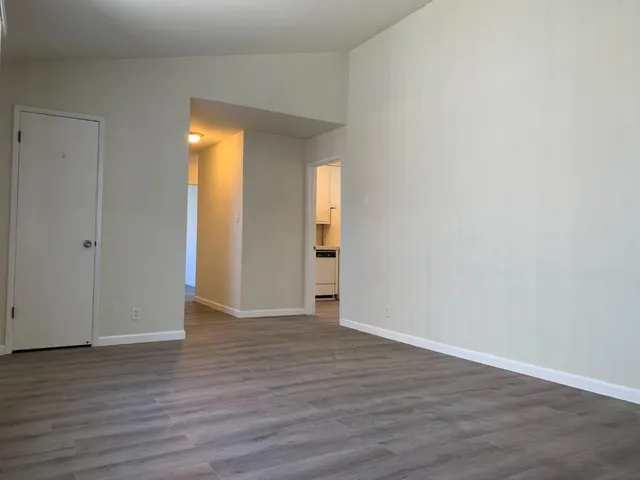 a view of an empty room with wooden floor and closet