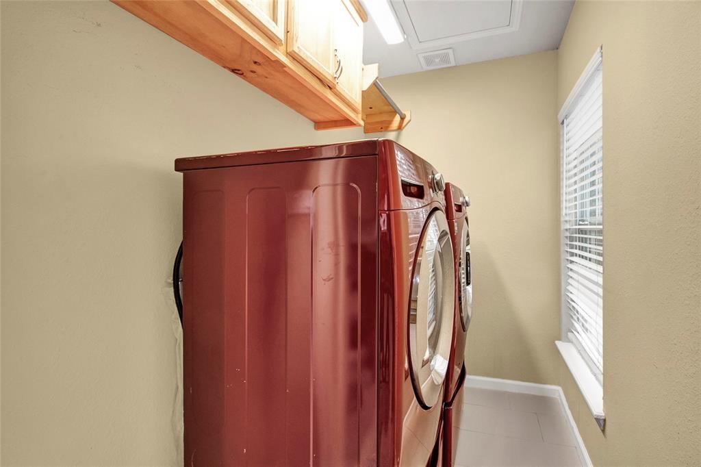 2078 Jeffcote Road Conroe, TX 77303 - Photo 18 of 19 This photo shows a compact laundry room with an overhead cabinet for storage and a window allowing natural light.