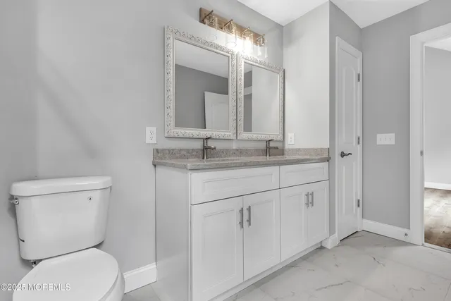 a bathroom with a granite countertop toilet sink and mirror