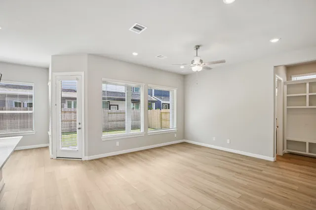 a view of an empty room with a window and wooden floor
