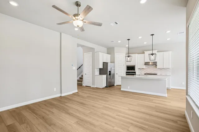 a large white kitchen with kitchen island a stove a refrigerator a sink dishwasher with a dining table and chairs