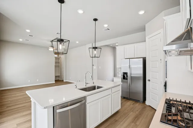 a kitchen with stainless steel appliances kitchen island a sink cabinets and wooden floor