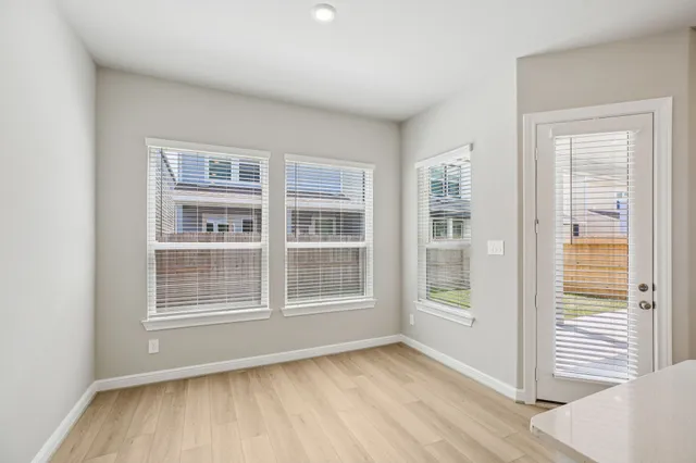 a view of an empty room with wooden floor and windows