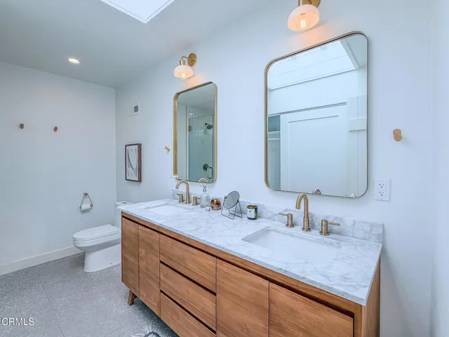 a bathroom with a granite countertop sink mirror and toilet