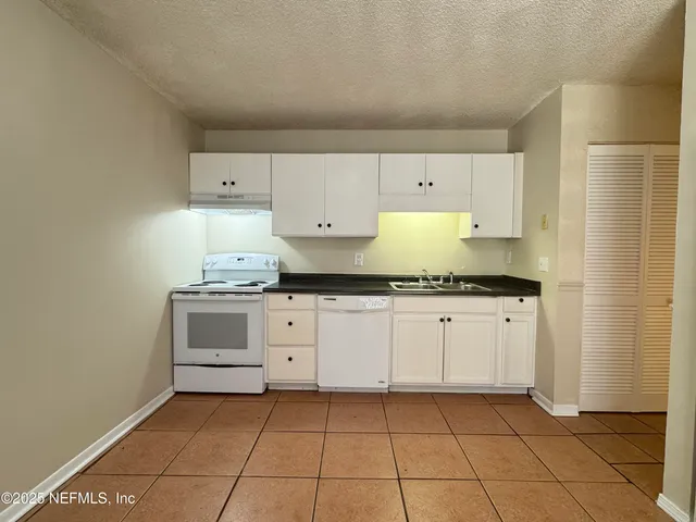 a kitchen with granite countertop a sink and a stove