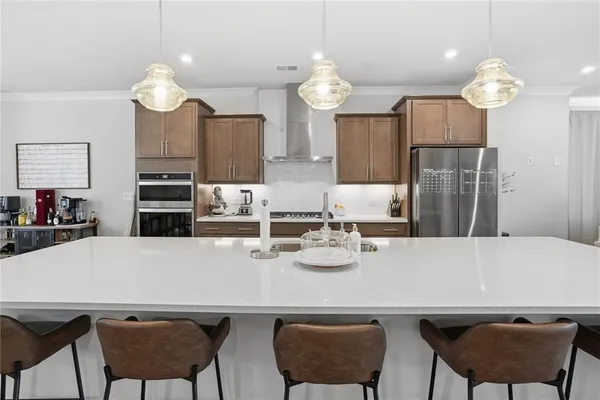 a large kitchen with stainless steel appliances a large counter top a stove a chimney a sink and a refrigerator