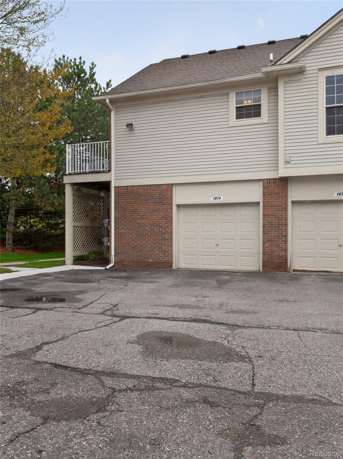 1834 Flagstone Circle, Unit 37 Rochester, MI 48307 - Photo 27 of 31 View of side of home featuring an attached garage, brick siding, a balcony, and driveway