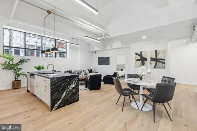 a living room with stainless steel appliances kitchen island granite countertop furniture and a wooden floor