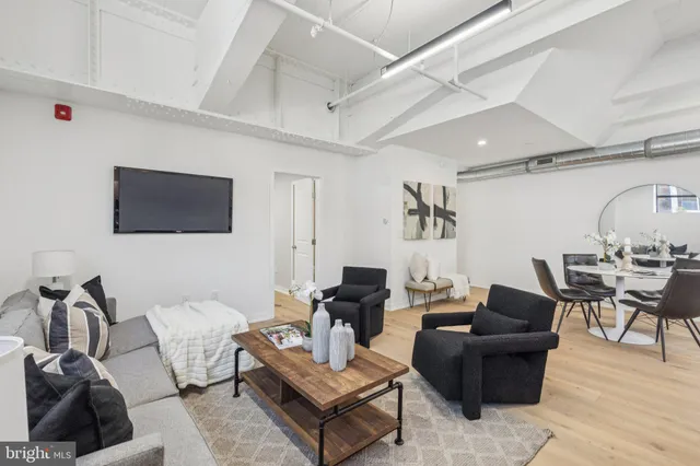 a living room with furniture a flat screen tv and kitchen view
