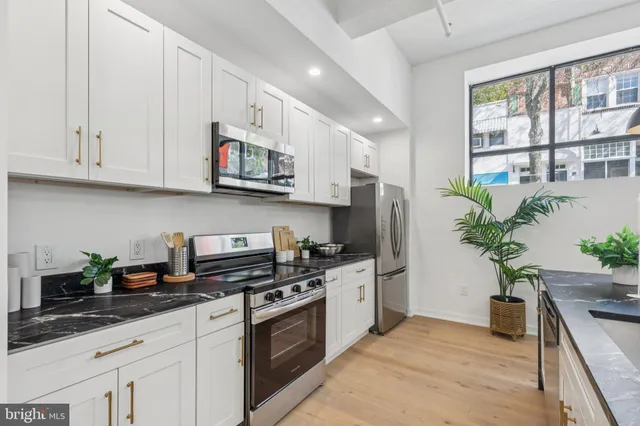 a kitchen with stainless steel appliances granite countertop a refrigerator a stove a sink dishwasher and white cabinets with wooden floor