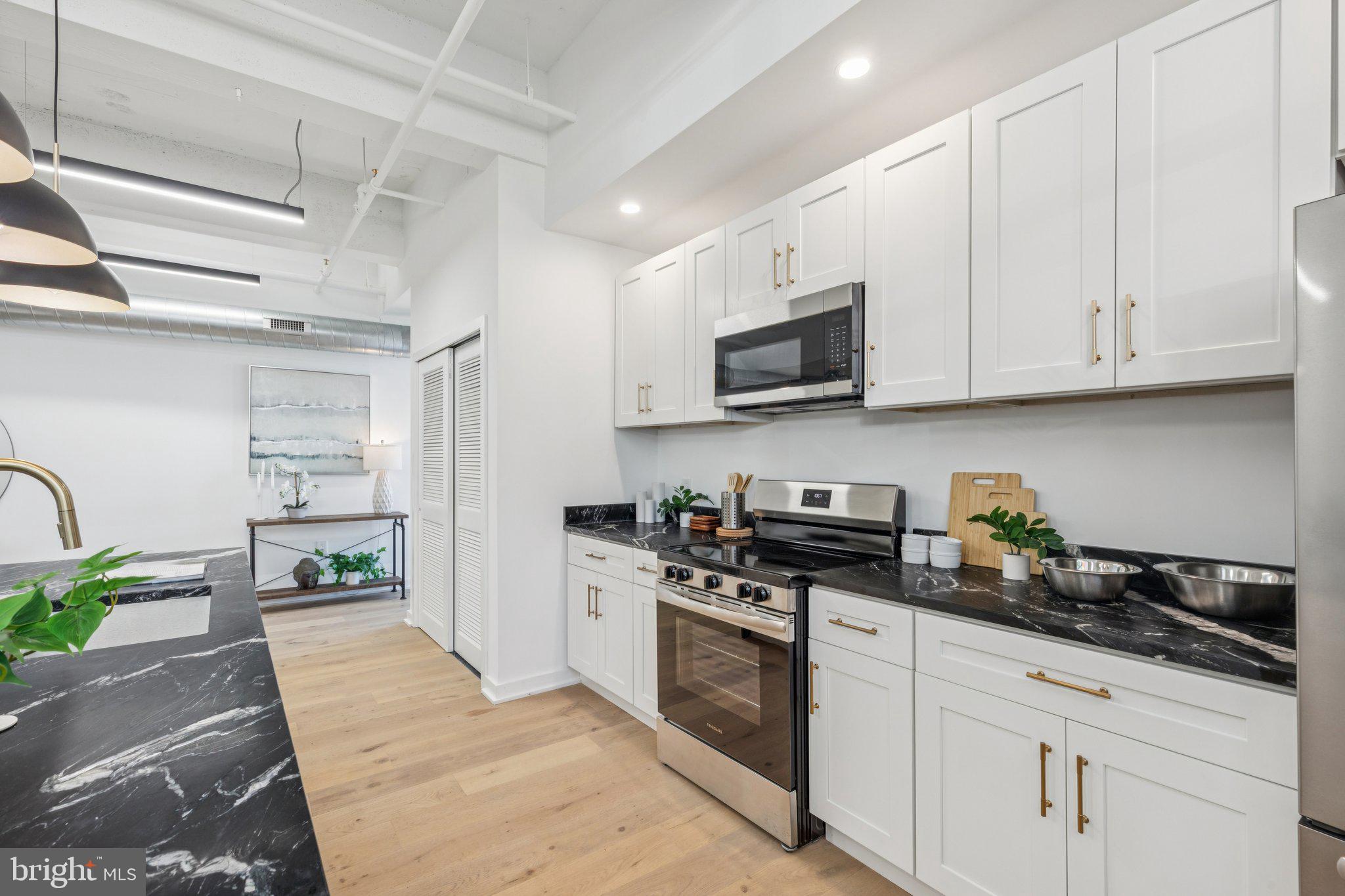36 North Narberth Avenue, Unit 1C Narberth, PA 19072 - Photo 30 of 36 a kitchen with stainless steel appliances granite countertop a stove a sink dishwasher and a microwave oven with white cabinets